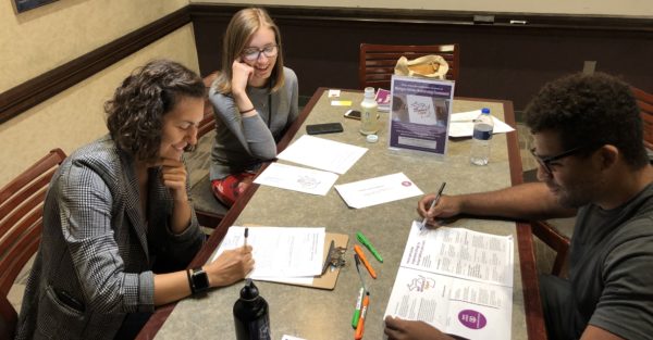 Two people take notes while watching a participant read the application. 