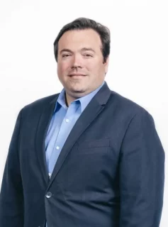 Photo of Adam Ambrogi, a man with brown hair wearing a blue suit.